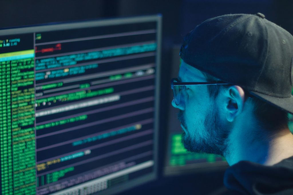 pexels photo 6963098 6963098 A cybersecurity expert inspecting lines of code on multiple monitors in a dimly lit office.